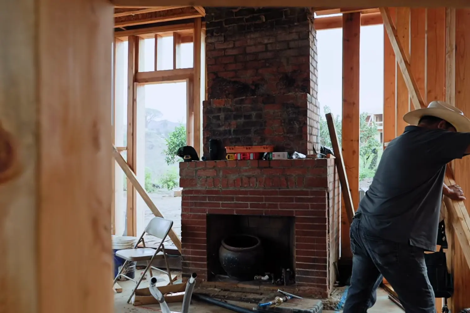 A framed interior wall opened up around a brick fireplace during a remodel
